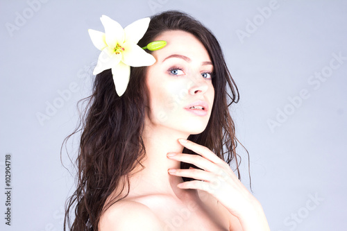 Beautiful woman with flower in curly hair touching her neck. Bea