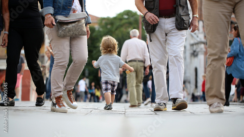 Baby boy walking in crowd