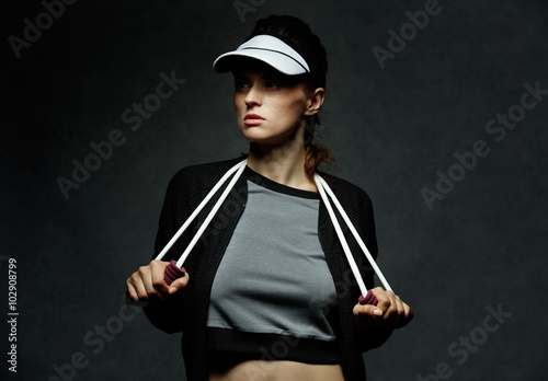 Young fit woman holding resistance band against dark background