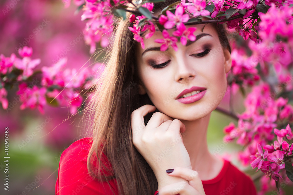Naklejka premium Happy beautiful young woman in spring blossom park. 
