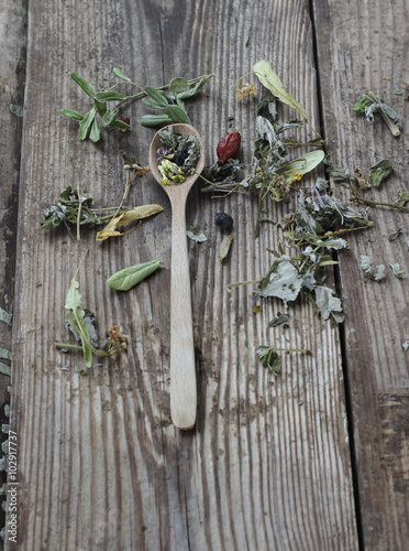 Spoon of mixed dried herb tea on wooden background