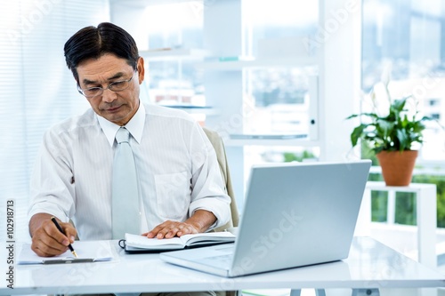 Focused asian businessman writing