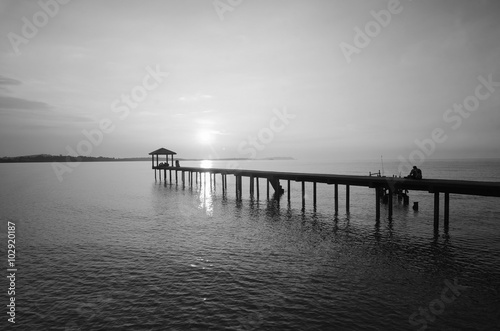 silhouette of a man sitting on the bridge alone in black and white