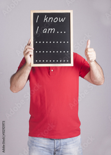 Man holding I Know I am... message written on a blackboard photo