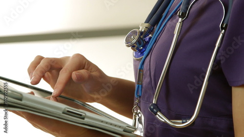 Close up of a young female nurse or doctor working with a digital tablet pc.