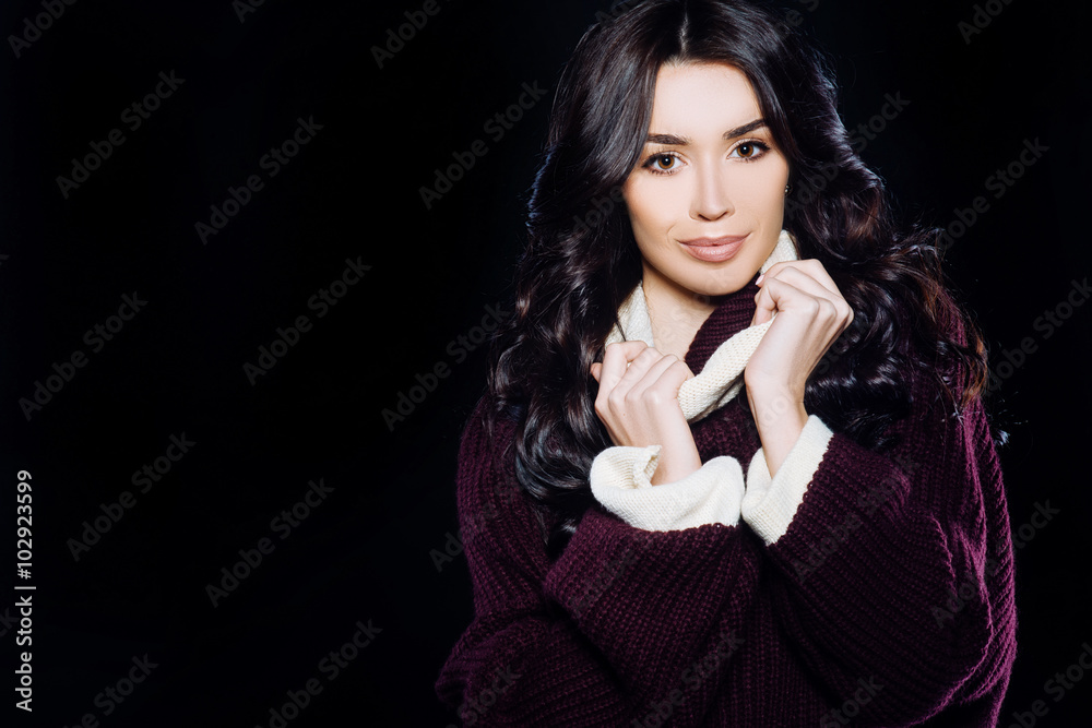 beautiful brown-eyed brunette girl model smiling with natural makeup and hair in a warm sweater on a black background beautiful brown-eyed brunette girl model smiling with natural makeup and hair in a warm sweater on a black background