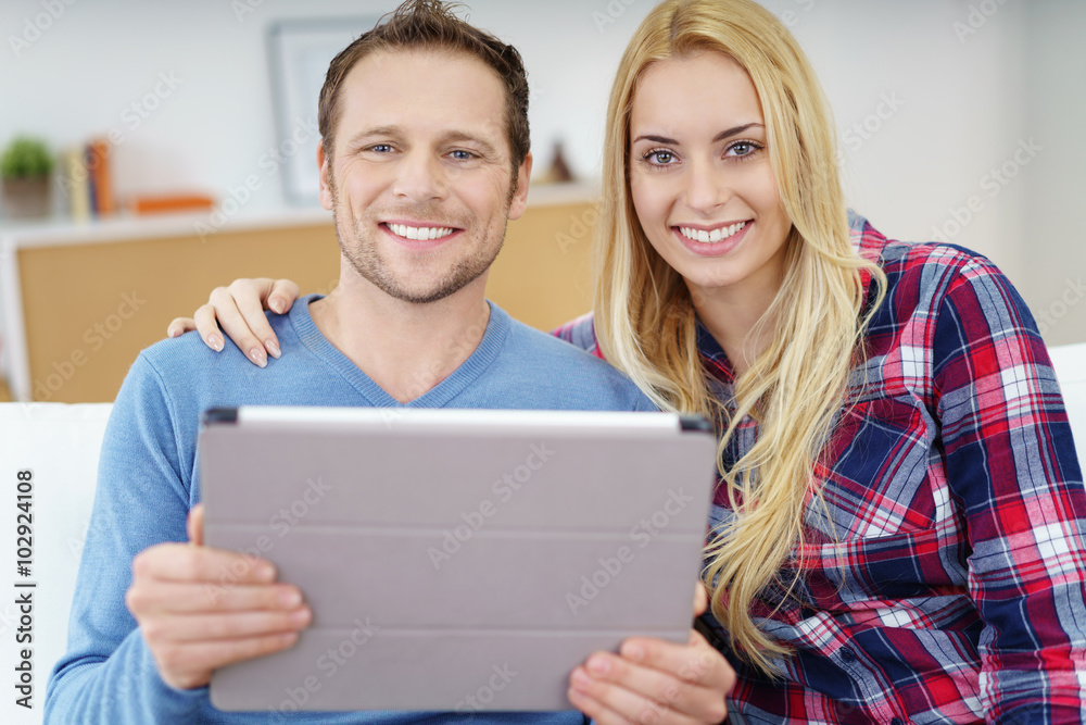 entspanntes junges paar mit tablet schaut in die kamera und lächelt entspanntes junges paar mit tablet schaut in die kamera und lächelt