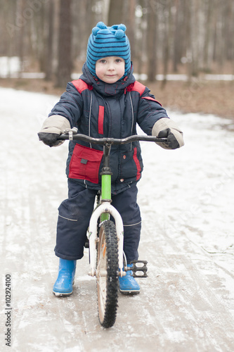Little boy riding a bicycle in a park in winter