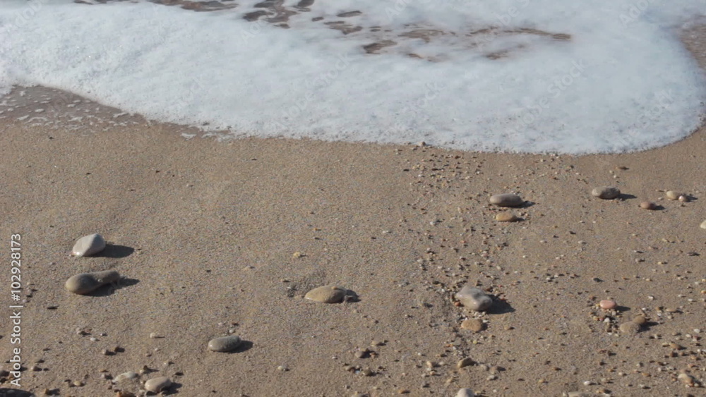 Close-up view of the pebbles, sand and waves at the beach Close-up view of the pebbles, sand and waves at the beach