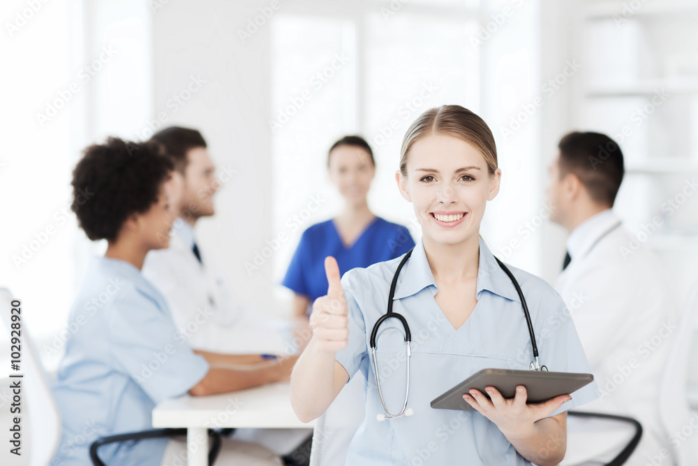 happy doctor with tablet pc over team at clinic happy doctor with tablet pc over team at clinic