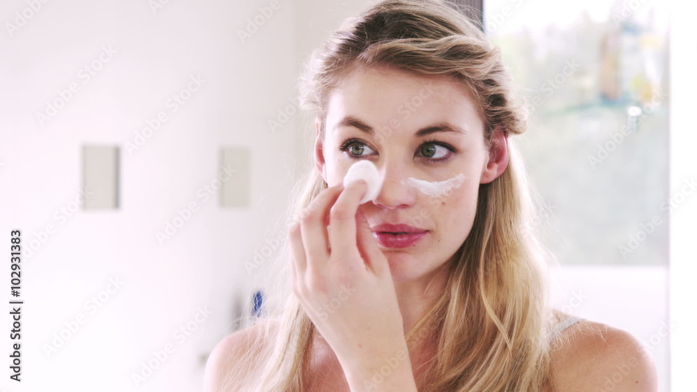 Pretty blonds applying cream on her face Pretty blonds applying cream on her face