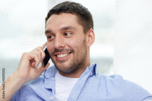 happy man calling on smartphone at home