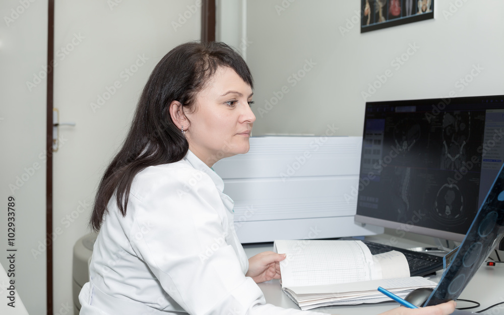 Brunette female doctor examining an CT scanner results Brunette female doctor examining an CT scanner results