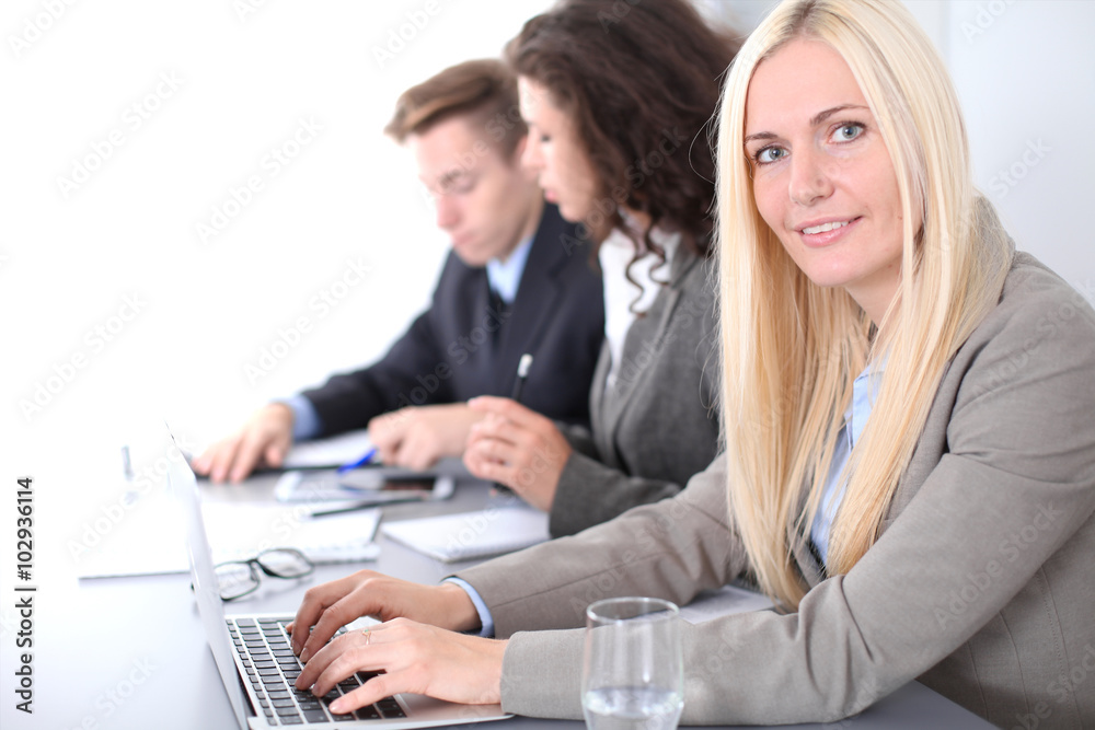 A group of business people at a meeting on the background of office. Focus on a beautiful blonde A group of business people at a meeting on the background of office. Focus on a beautiful blonde