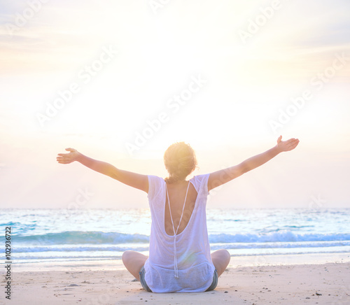 woman with hands up at sunrise beach