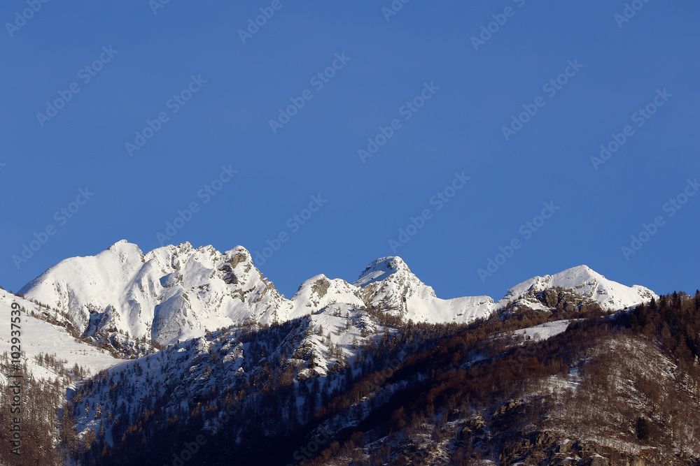 Mountain peaks and valley covered in snow with clear blue skies