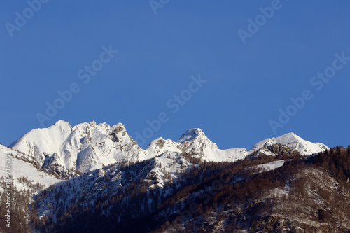 Mountain peaks and valley covered in snow with clear blue skies © miq1969