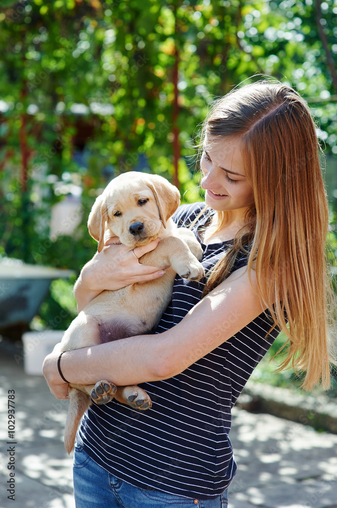 Portrait of Young woman holding on hands puppy Labrador Portrait of Young woman holding on hands puppy Labrador