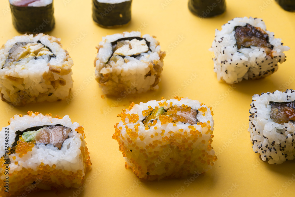 Various kinds of sushi food served on yellow blackground Various kinds of sushi food served on yellow blackground