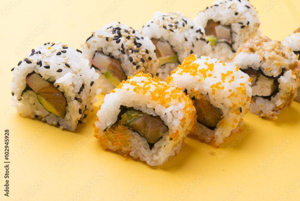 Various kinds of sushi food served on yellow blackground Various kinds of sushi food served on yellow blackground