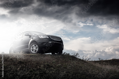 Black car stay on hill in dramatic clouds at daytime photo