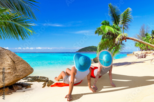Fototapeta Naklejka Na Ścianę i Meble -  Two women with hats enjoying sun holidays on the tropical beach