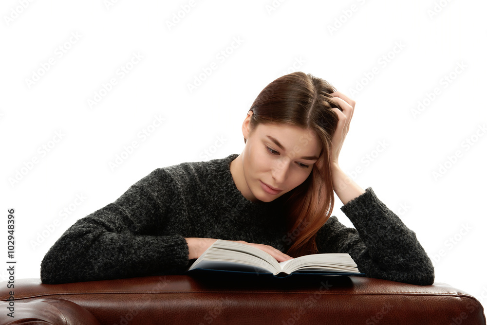 Young woman with book leaning on leather furniture