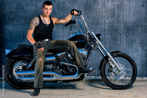 Tough, tattooed fighter with his bike in chopper-style