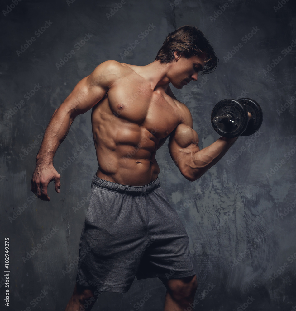 Shirtless muscular man holding a dumbbell.