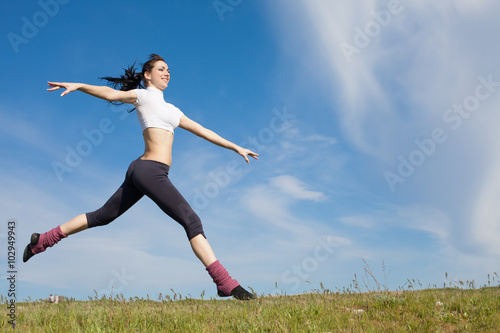 Attractive young woman jumping on open air