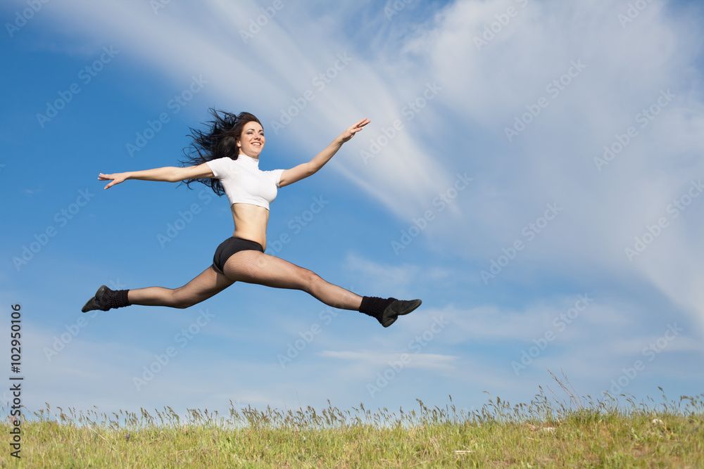 Attractive young woman jumps on background of sky Attractive young woman jumps on background of sky