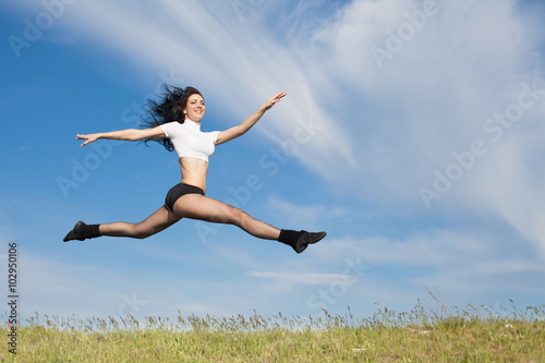 Attractive young woman jumps on background of sky