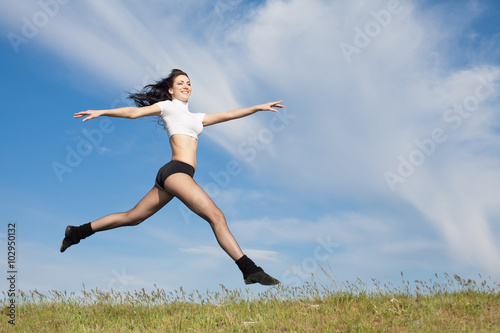 Attractive young woman jumping on open air