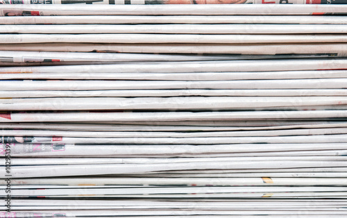 View of a pile of newspapers stacked isolated on a white background.