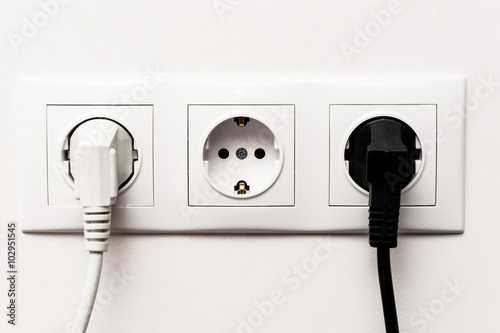 Triple electrical socket with two plugged cables.