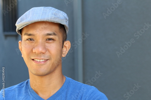 Canvas Print Portrait of a smiling Asian man in newsboy hat looking to camera