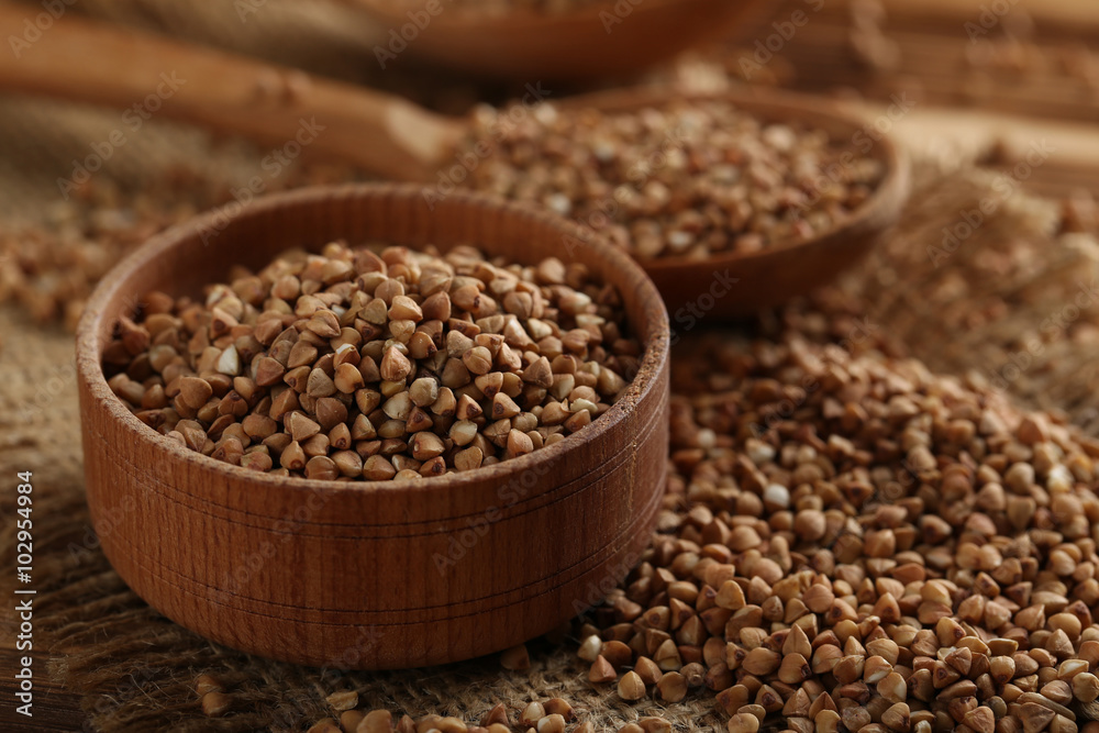 Buckwheat seeds in bowl on a brown wooden table Buckwheat seeds in bowl on a brown wooden table