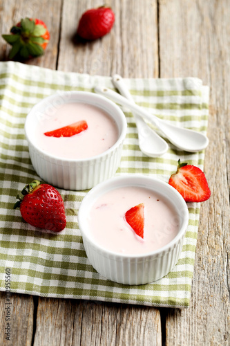 Strawberry yogurt in bowl on a grey wooden table