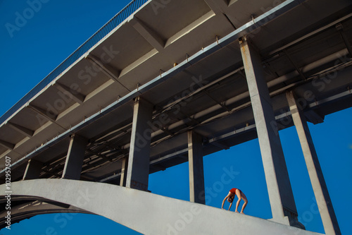 Young beautiful woman gymnast posing on bridge girder