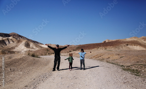 father hiking with two kids in the desert