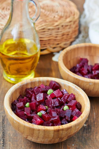 Homemade beetroot salad with green peas in a wooden bowl