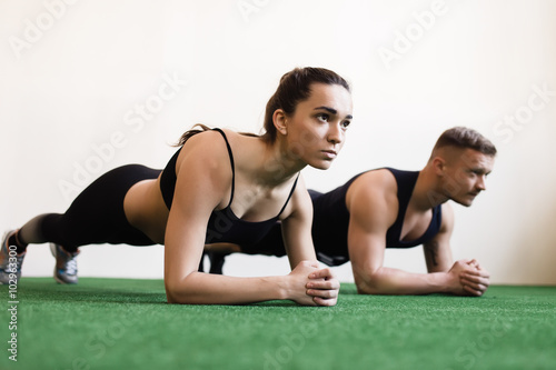 Man and woman doing plank exercises at the gym