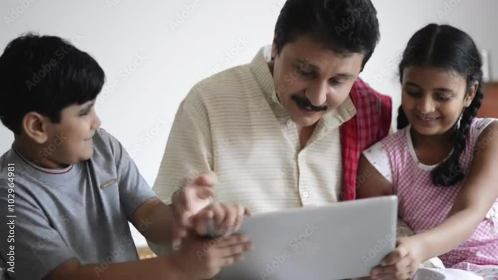 Locked-on shot of children fighting for a laptop with their father sitting near them Locked-on shot of children fighting for a laptop with their father sitting near them