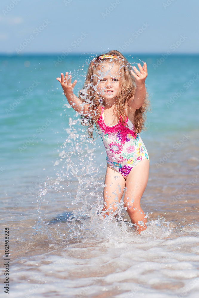 Fototapeta premium happy girl on a beach has a fun with splash