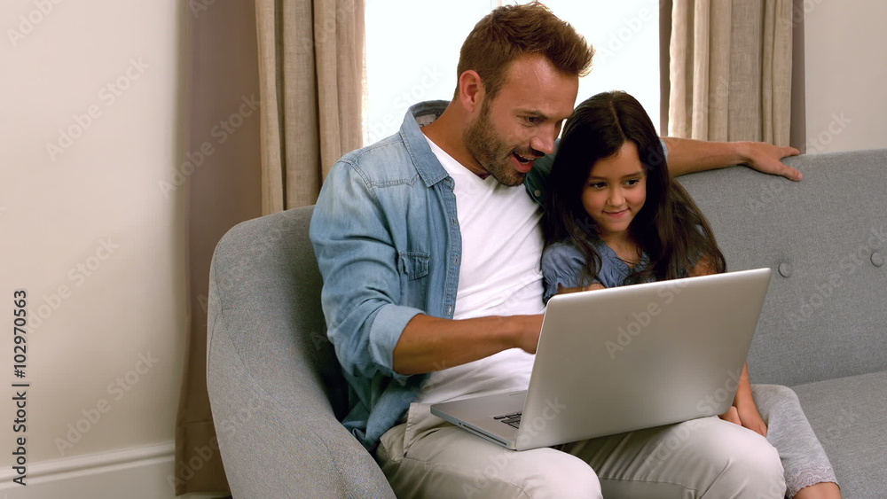 Happy father and daughter using laptop on the sofa Happy father and daughter using laptop on the sofa