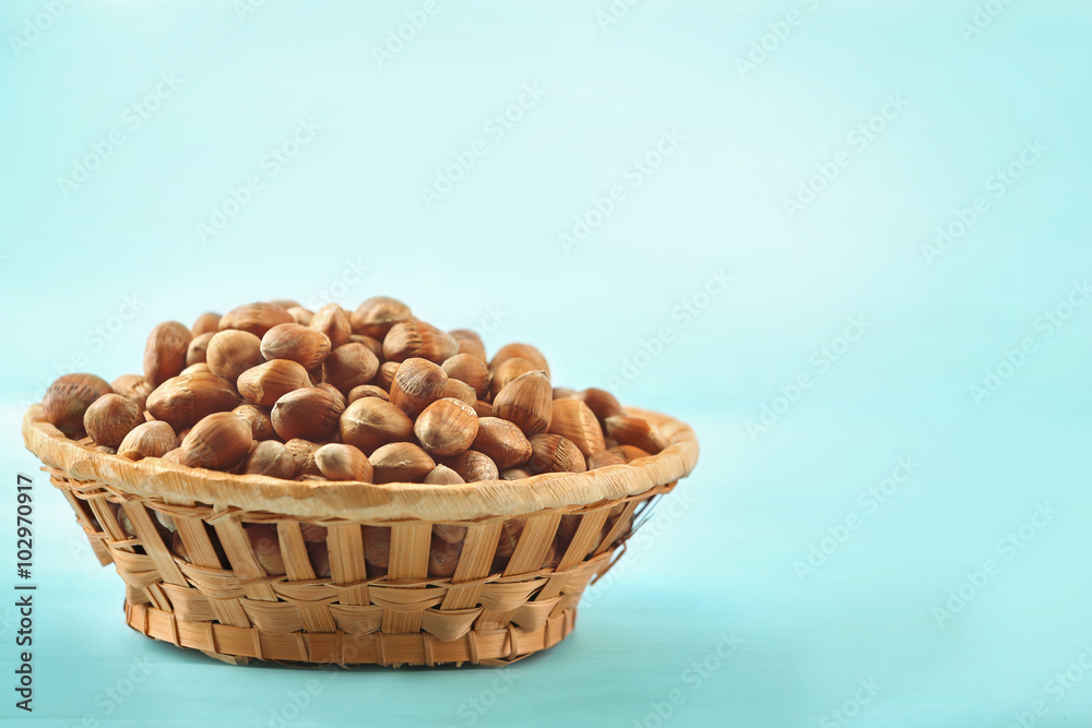 Hazelnuts in wicker basket on color wooden background Hazelnuts in wicker basket on color wooden background