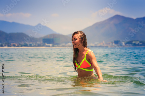 blonde slim girl in bikini stands half body in sea looks forward © SlavaStock