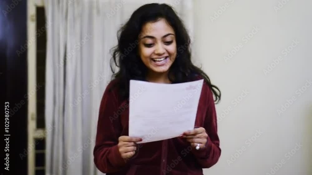 Locked-on shot of an excited woman reading a letter