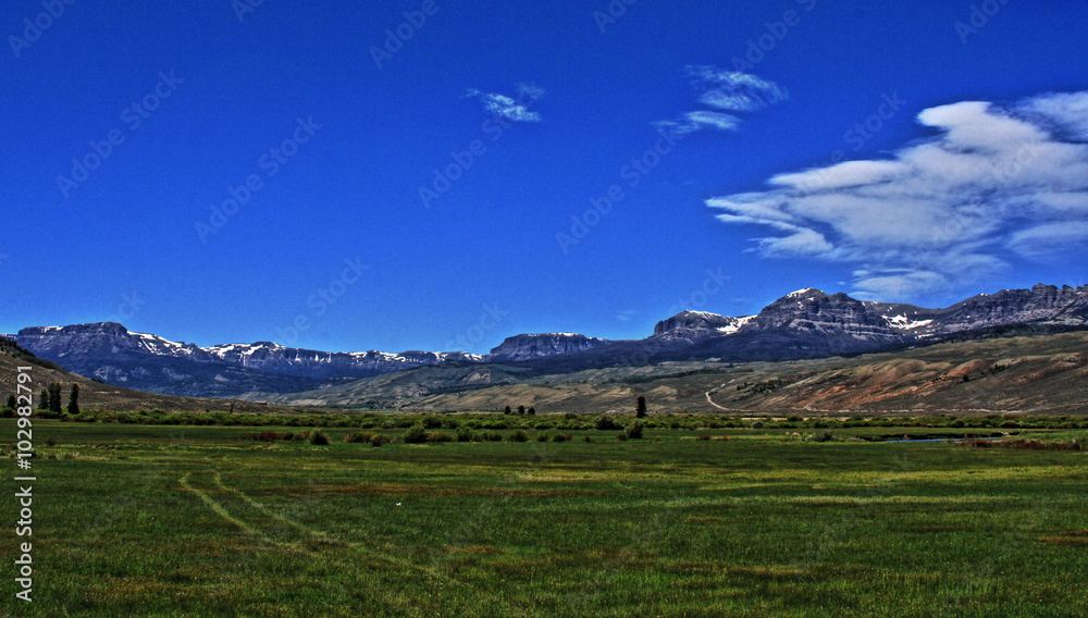 Dubois Wyoming pasture / farming field under cumulus / cirrus cloudscape with Absaroka Mountain range in the background Dubois Wyoming pasture / farming field under cumulus / cirrus cloudscape with Absaroka Mountain range in the background