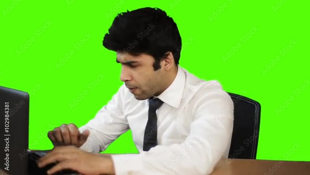 Businessman working on a laptop in office against green background Businessman working on a laptop in office against green background
